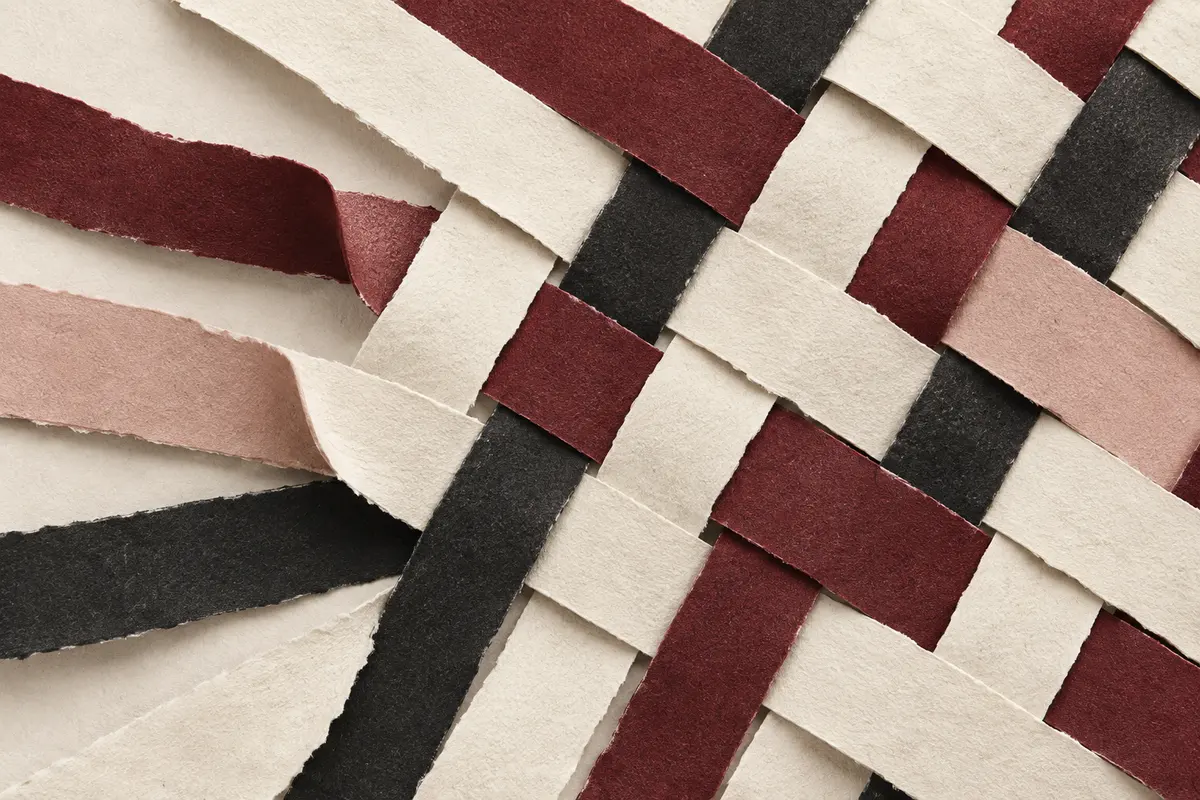 Paper strips woven into a shared fabric, representing connected management systems.